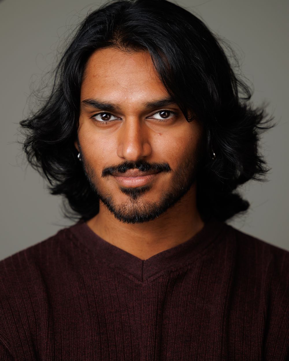 Theatrical actor headshot on a gray backdrop with a grounded, serious expression, HeadshotDC