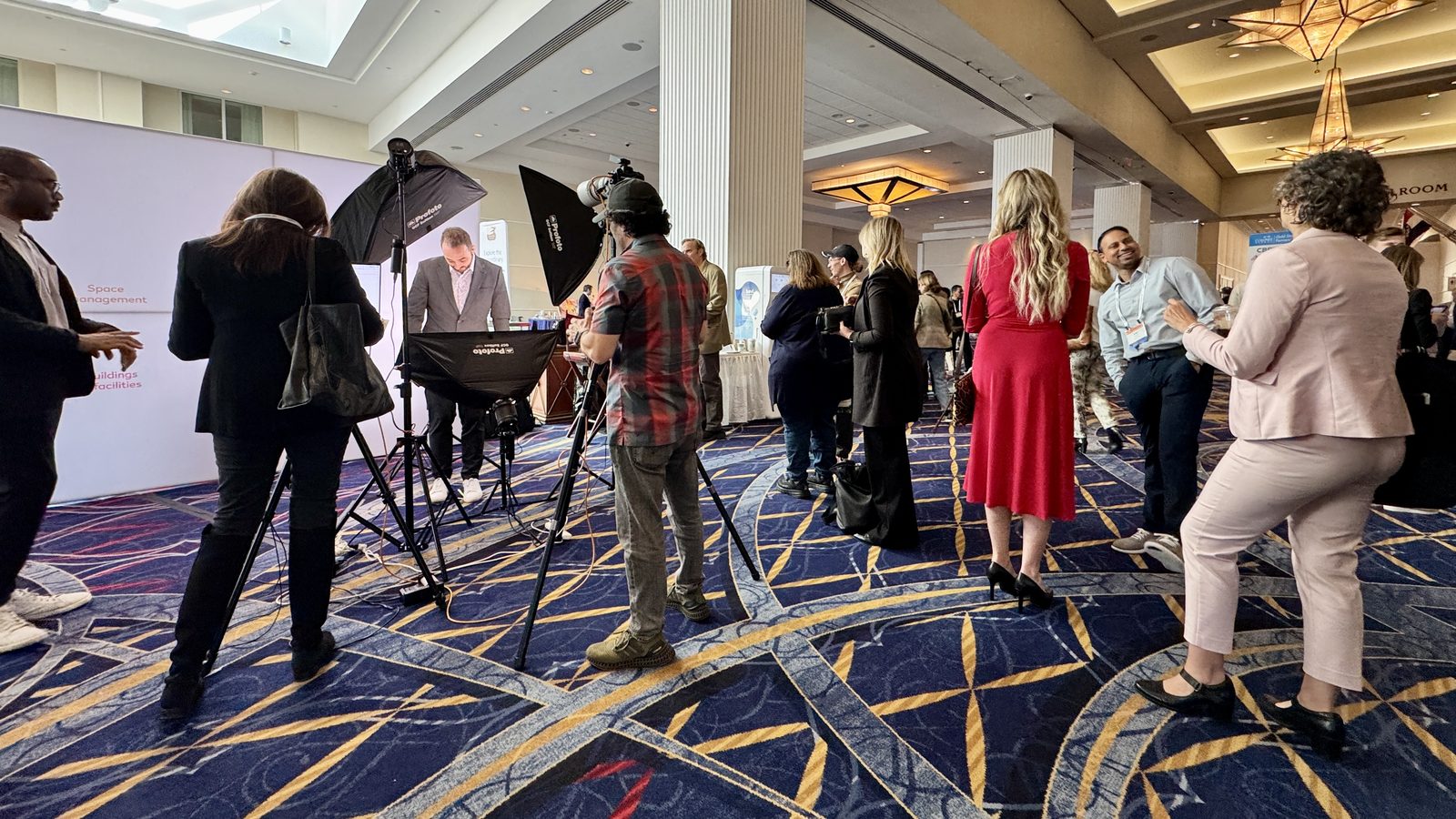 Attendees waiting in line at a HeadshotDC headshot station inside an expo hall, with studio lighting and a branded backdrop