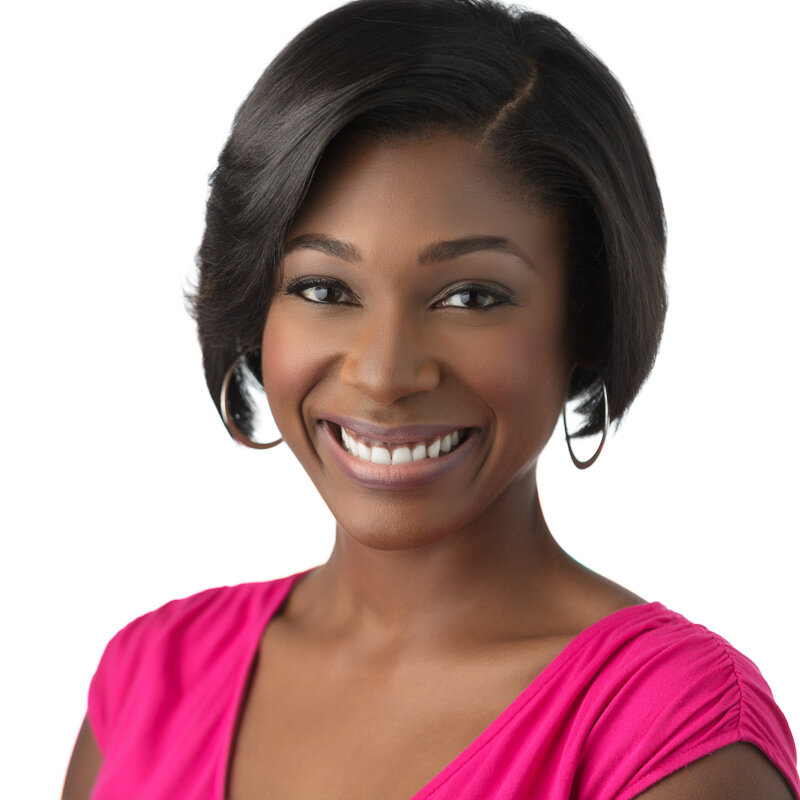 A smiling African American woman with short black hair, wearing hoop earrings and a bright pink top, against a white background.